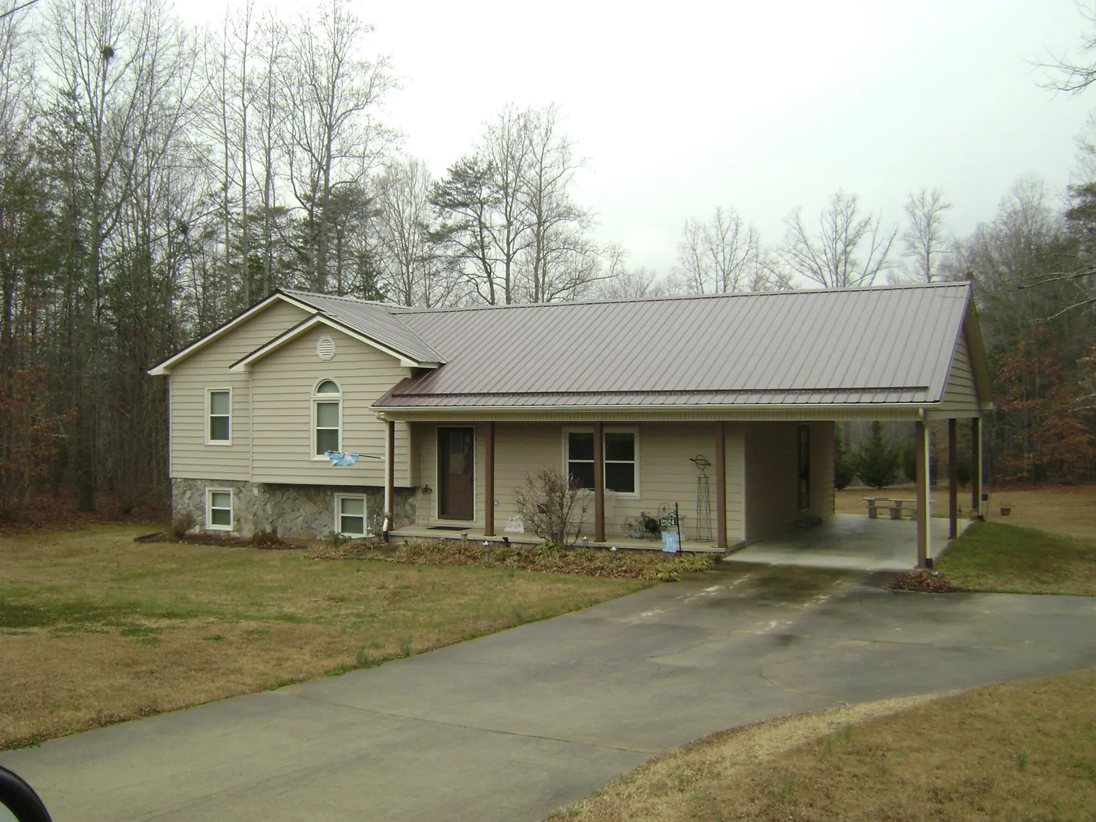 Brown metal roof on a tan split level home with an attached carport in Woodstock